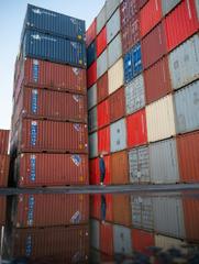 Photo of a man staring at a high stack of shipping containers.